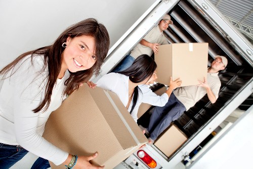 Movers carrying furniture from a Barnes flat during an urgent relocation